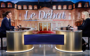 French President Emmanuel Macron (L) and French far-right party Rassemblement National (RN) candidate Marine Le Pen (R) sit prior to taking part in a live televised debate on French TV