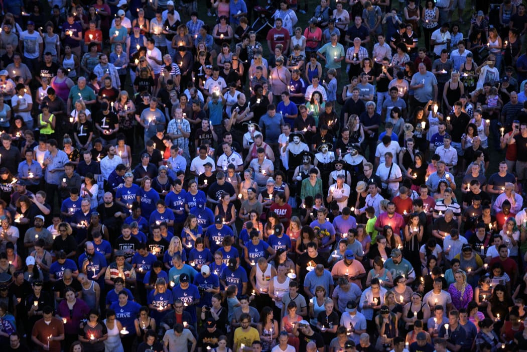 Mourners hold candles while observing a moment of silence during a vigil outside a performing arts centre in Orlando.