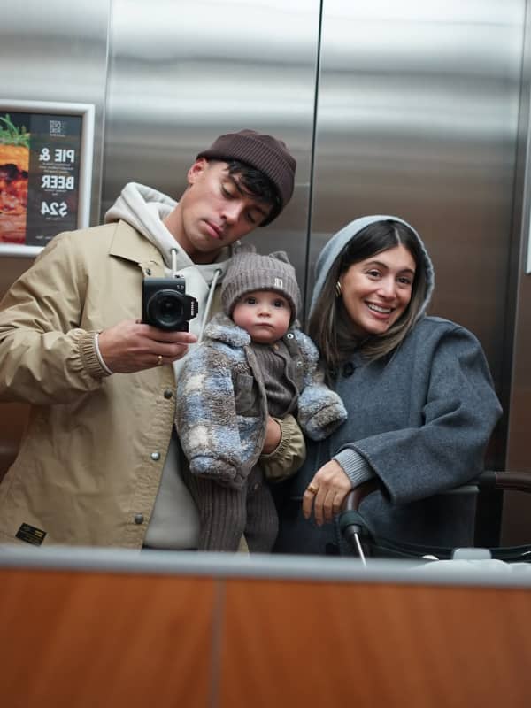 A young couple with a baby in an elevator.