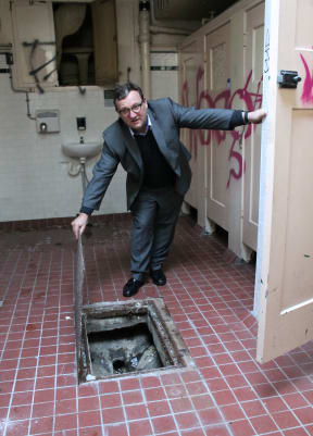Ian Reid from Auckland Council’s property team, holding open the lid to expose the original sewer under the now-closed Wellesley Street East women’s conveniences.
