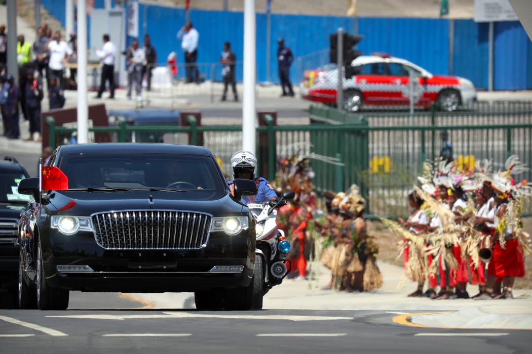 A limousine carrying China's President Xi Jinping drives past dancers in traditional attire. Port Moresby, November 16, 2018.