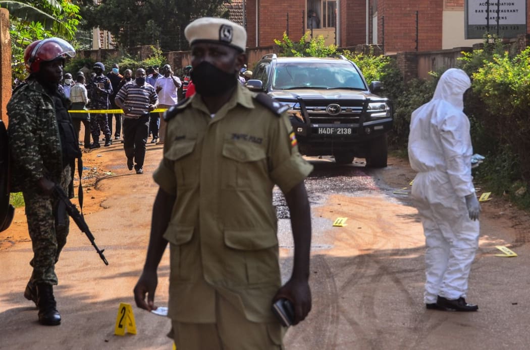 Police officers secure and investigate the crime scene with the car of General Katumba Wamala. Uganda's transport minister, who used to lead the armed forces, was shot Tuesday in an attack which left his daughter and bodyguard dead.