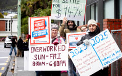 A Wellington protester’s sign makes reference to Public Service Minister Judith Collins’ error when she said that on average a teacher with 10 years’ experience was on an annual salary of $140,000. Collins later said she mixed up her messages and had apologised for the error.
