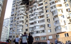 People stand outside an apartment block in the Solomianskyi district damaged by an overnight Russian attack in Kyiv, Ukraine, on June 6, 2025. On Friday night, June 6, four people die and at least 20 others are injured in a Russian missile and drone attack on Kyiv. In particular, three rescuers of the State Emergency Service of Ukraine die and nine others are injured while responding to the consequences of the nighttime attack in the Ukrainian capital. Falling debris and strikes are reported in six districts of Kyiv. (Photo by Kirill Chubotin/Ukrinform) NO USE RUSSIA. NO USE BELARUS. (Photo by Ukrinform/NurPhoto) (Photo by Kirill Chubotin / NurPhoto via AFP)