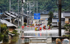 Fire fighters conduct researches at the residential area covered with water in Kurashiki, Okayama Prefecture on July 8, 2018.