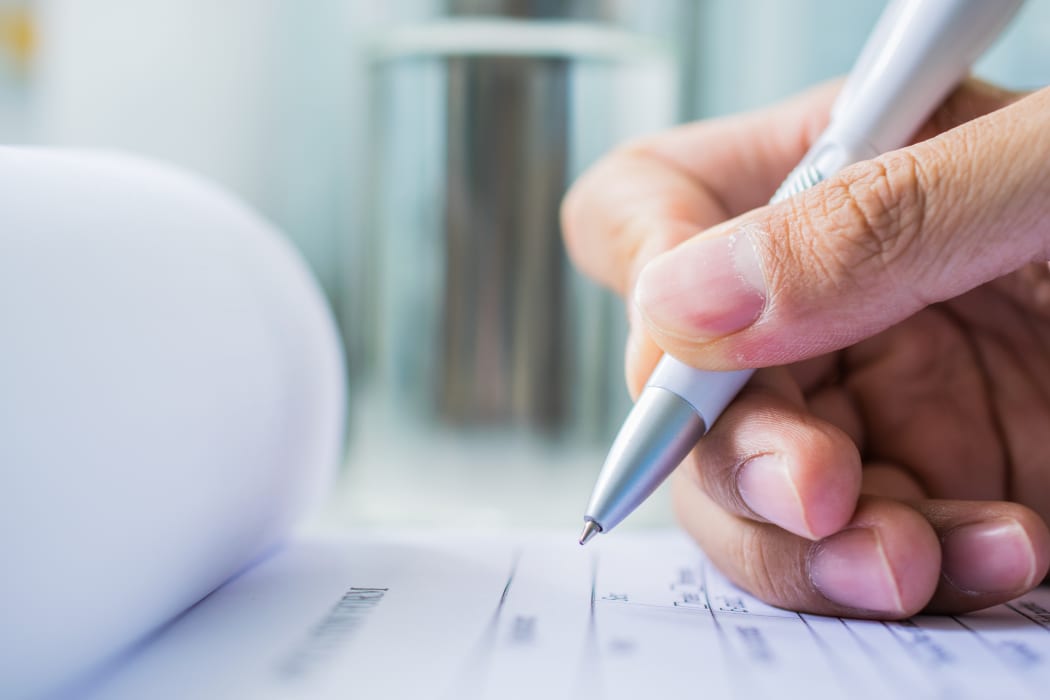 Hand with pen over application form on blure water glass background