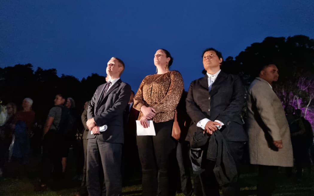 The crowd moves to the open field where the flag is being raised as dawn rises.