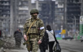 A Russian soldier patrols in a street of Mariupol on April 12, 2022, as Russian troops intensify a campaign to take the strategic port city, part of an anticipated massive onslaught across eastern Ukraine, while Russia's President makes a defiant case for the war on Russia's neighbour.
