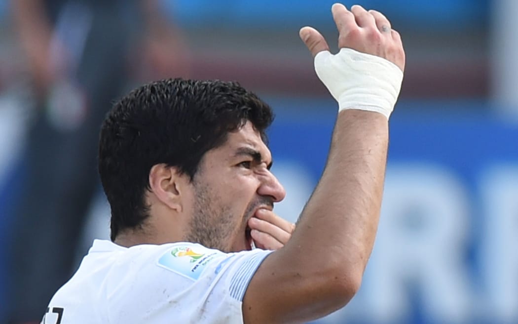 Uruguay forward Luis Suarez puts his hand to his mouth after clashing with Italy's Giorgio Chiellini.