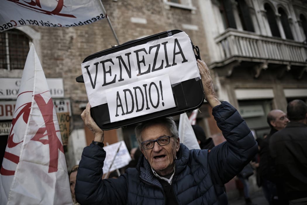 A man holds a luggage bearing the slogan "Goodbye Venice" during a demonstration against the increasing number of tourists in Venice, on November 12, 2016.