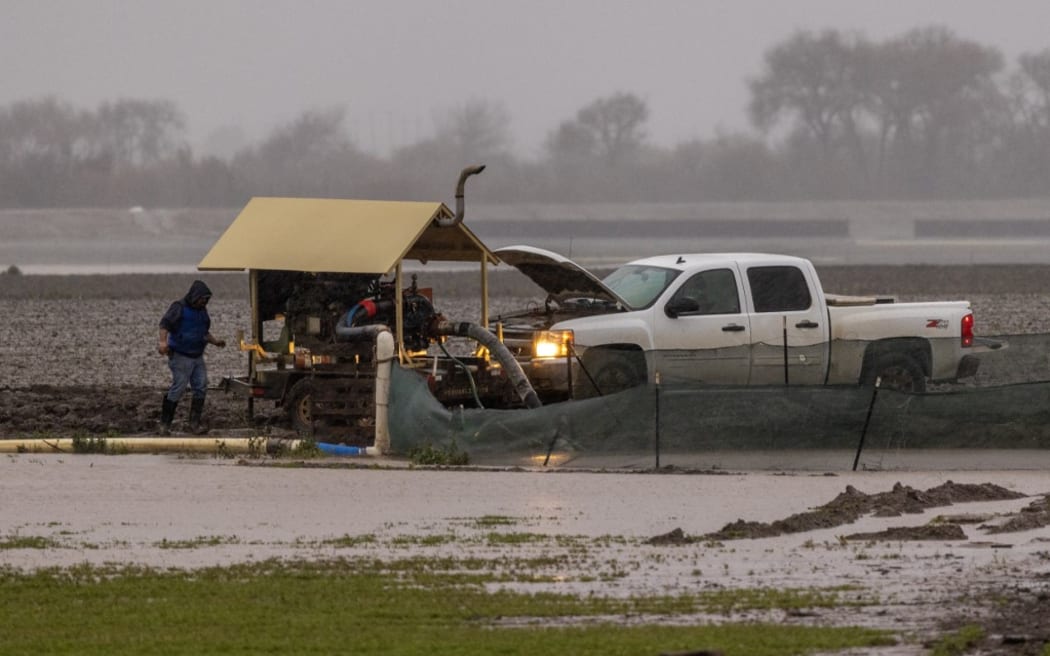 A farmer tends to a pump in a flooded field next to the Salinas River near Chualar, California.