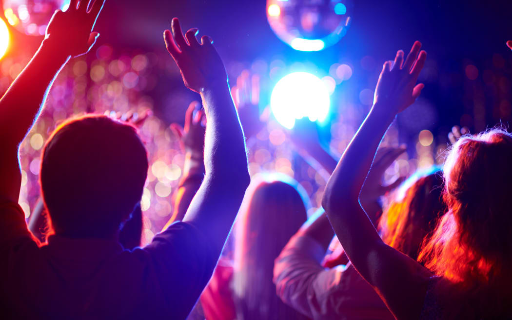 Crowd of people with raised arms dancing in night club