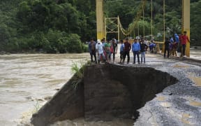 People look at the damage caused by heavy rains brought by Hurricane Eta, now degraded to a tropical storm, on a bridge over the overflooded Cahaboncito river in Panzos, Alta Verapaz, 220 km north of Guatemala City on November 6, 2020.