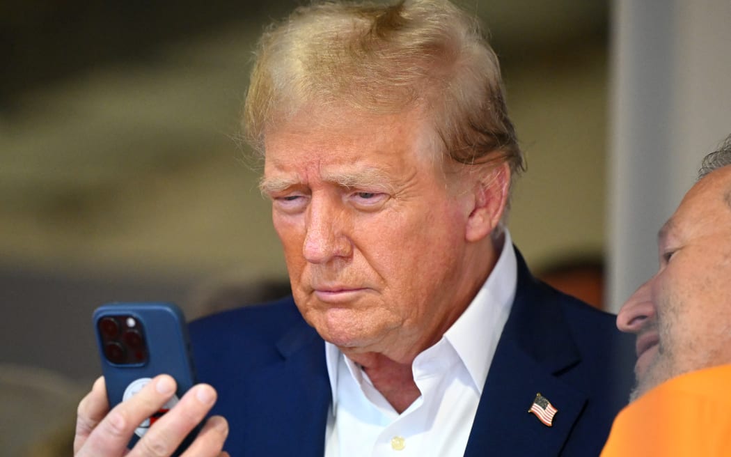 MIAMI, FLORIDA - MAY 05: Donald Trump talks on the phone in the McLaren garage prior to the F1 Grand Prix of Miami at Miami International Autodrome on May 05, 2024 in Miami, Florida.   Clive Mason/Getty Images/AFP (Photo by CLIVE MASON / GETTY IMAGES NORTH AMERICA / Getty Images via AFP)
