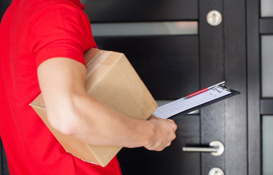 Delivery guy waiting at front door with a parcel.