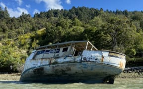 Old and damaged wooden fishing boat aground in Marlborough Sound