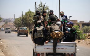 Tribal and bedouin fighters cross Walga town as they mobilise amid clashes with Druze gunmen, near the predominantly Druze city of Sweida in southern Syria on July 19, 2025. Syrian Bedouins and their allies fought Druze gunmen in the community's Sweida heartland for a seventh day despite a ceasefire ordered by the government following a US-brokered deal to avert further Israeli military intervention. (Photo by Abdulaziz KETAZ / AFP)