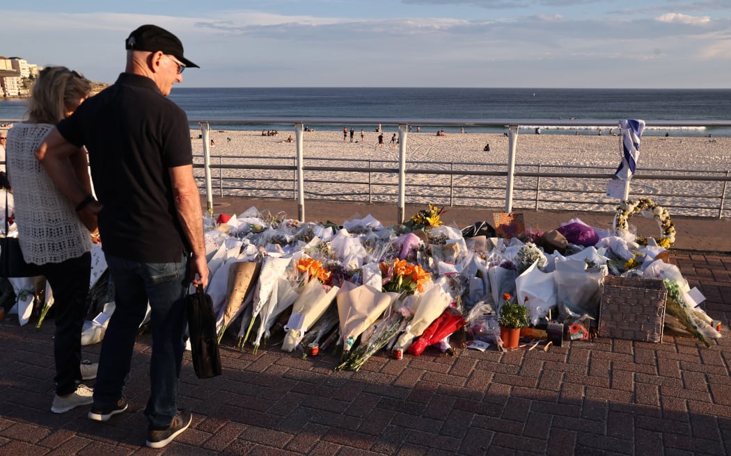 Mourners look at flowers laid next to the beach in memory of victims of the shooting at Bondi Beach, in Sydney, on 20 December, 2025.