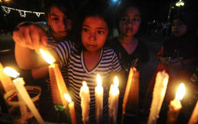 Girls in the southern Thai province of Narathiwat light candles to the late king,  Bhumibol Adulyadej