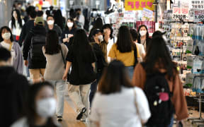 People wearing face masks walk through an underground shopping area in Seoul on May 6, 2020.