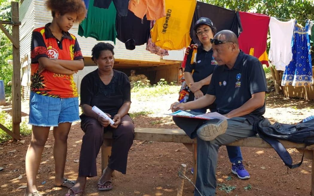 A Papua New Guinea census official helping people fill out census forms for the 2021 census, in 2020.