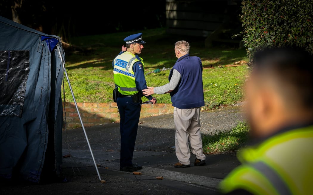 Outside the cordon a resident talks to police.