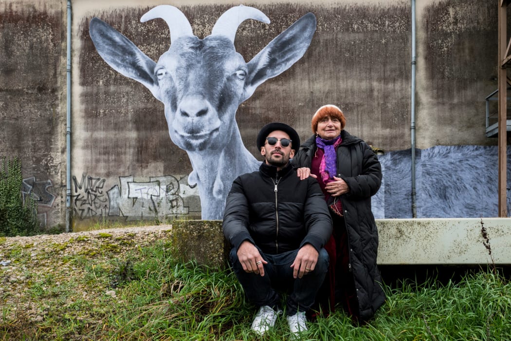 Artist JR and filmmaker Agnès Varda pose in front of one of JR’s pasted artworks.