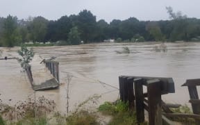 The swing bridge over the Tukituki River, Hawkes Bay, was swept away in the flooded river.