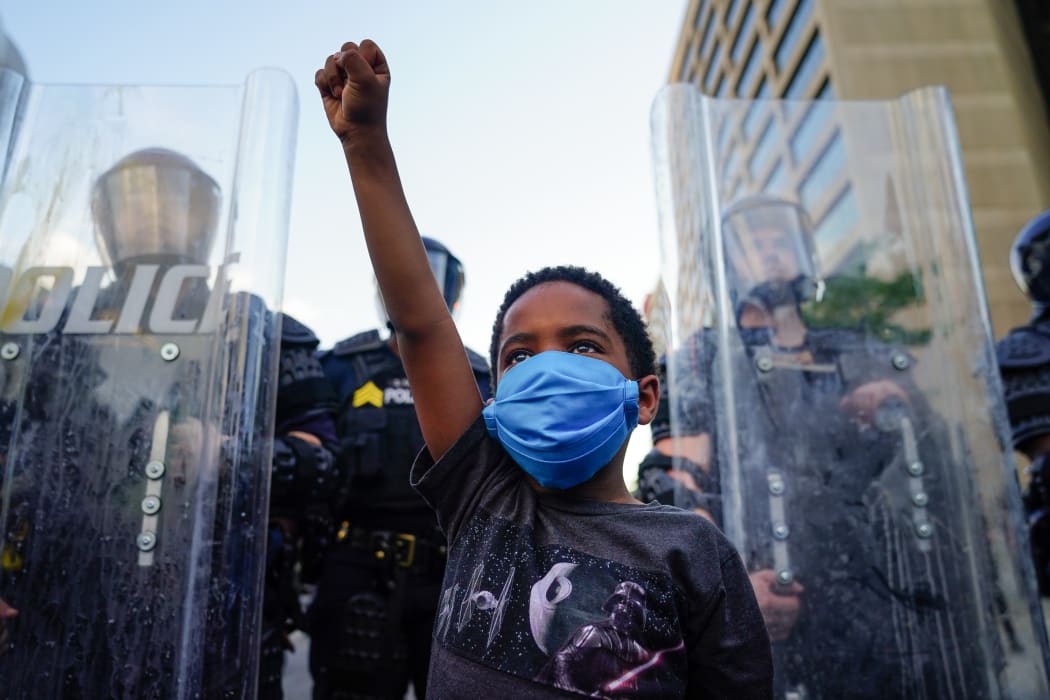 A young boy raises his fist for a photo by a family friend during a demonstration on May 31, 2020 in Atlanta, Georgia.