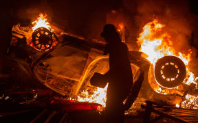 A car is set on fire during a protest in Yogyakarta on August 29, 2025, following the death of a motorcycle taxi driver who was run over by an armoured Brimob (Mobile Brigade Corps) vehicle the night before. Protests erupted across several Indonesian cities on August 29 in anger at the death of a motorcycle taxi driver hit by a police vehicle, as officers responded with tear gas and the president called for calm. (Photo by Devi RAHMAN / AFP)