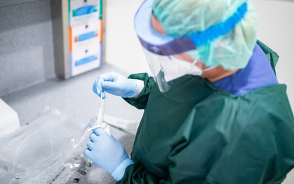 Person in protective clothing and with a breathing mask in an airlock.