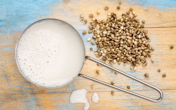 hemp milk in measuring cup with seeds