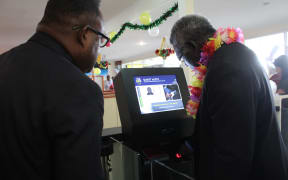 Solomon Islands Prime Minister Manasseh Sogavare (R) tries out the newly launched E-passport and Border Control and Management system. Looking on (L) is the Deputy Prime Minister Manasseh Maelanga.