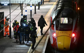 Police and British Transport Police officers walk on the platform alongside an LNER Azuma train at Huntingdon Station in Huntingdon, eastern England, on November 1, 2025, following a stabbing on a train. UK police said they had arrested two suspects Saturday as "a number of people" were taken to hospital after a stabbing on a train in Cambridgeshire, eastern England. "We are currently responding to an incident on a train to Huntingdon where multiple people have been stabbed," British Transport Police said on X, adding that "two people have been arrested". (Photo by JUSTIN TALLIS / AFP)