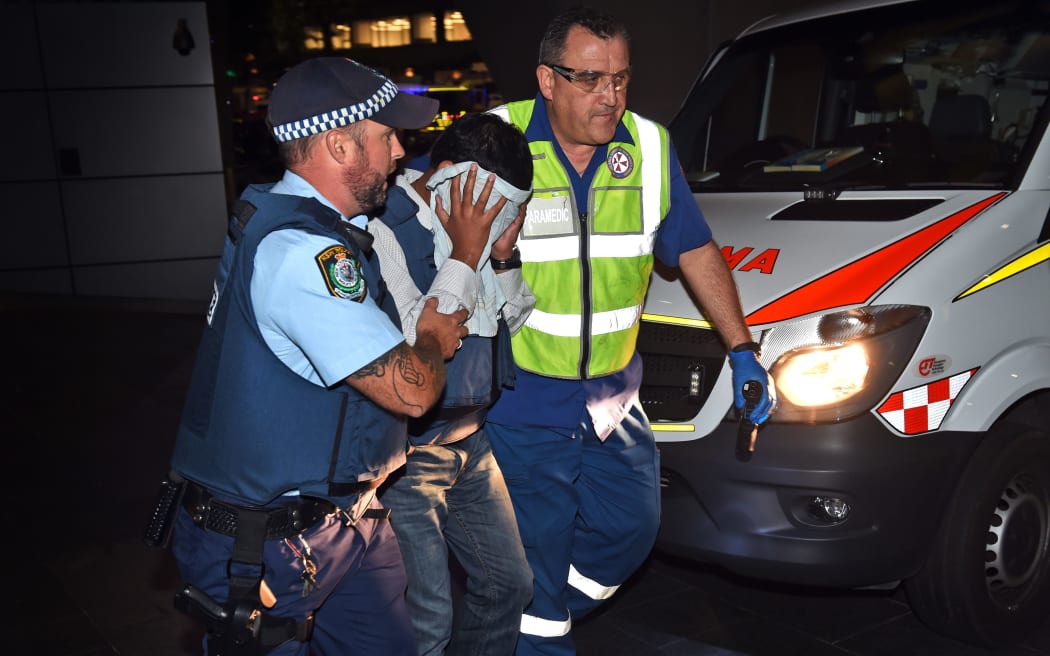 A policeman and a paramedic escort a hostage away from the scene during the siege at Lindt Chocolate Cafe in Martin Place, Sydney, December 2014.