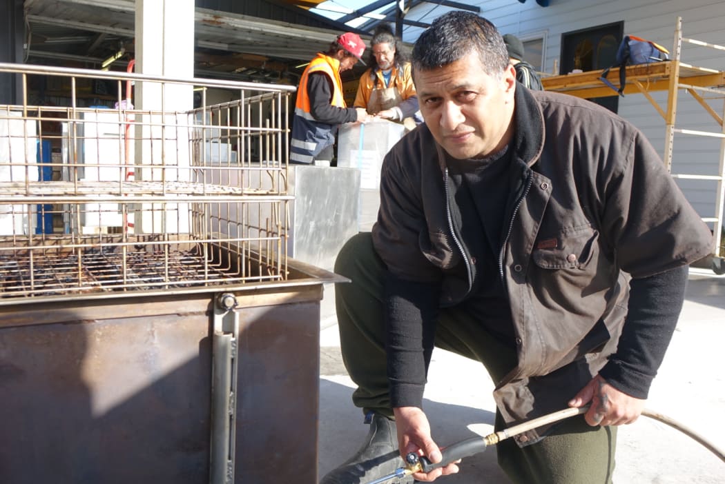 Owner of Te Kohatu Hangi Cookers John Tipene demonstrates how the river stones are heated.