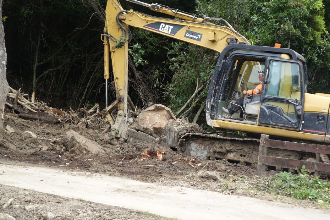 A digger helps clear forestry debris in Marahau after slips and flash flooding from Cyclone Gita.