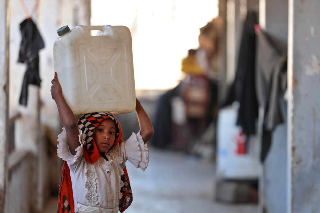 A girl carries a water container on her head at a school building for displaced Yemenis in the town of al-Turba in Taez on February 4, 2021.