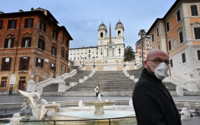 A man wearing a protection mask walks by the Spanish Steps at a deserted Piazza di Spagna in central Rome.