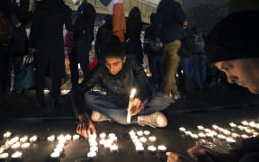 A man lights candles at a makeshift memorial in tribute to the victims of the Paris attacks at the place de la Republique in Paris on November 14, 2015. AFP PHOTO / JOEL SAGET
