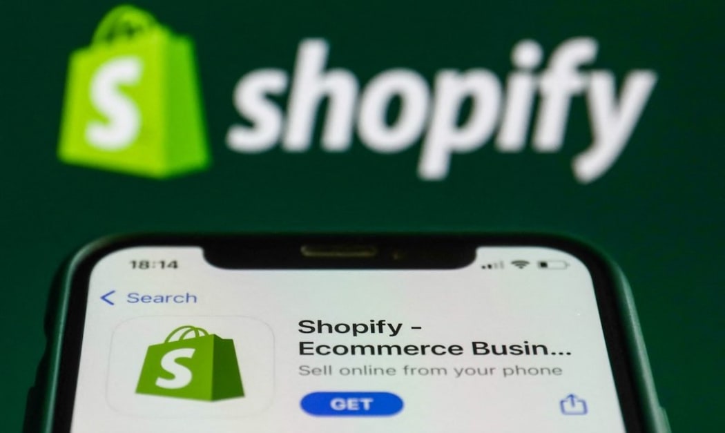 Shopify logo on the App Store and Shopify logo displayed on a laptop screen are seen in this illustration photo taken in Krakow, Poland on August 26, 2021.