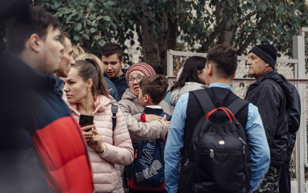 A woman hugs a boy surrounded by other people near the scene of a school shooting in Izhevsk on 26 September, 2022.