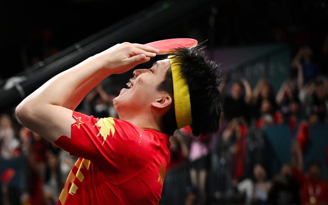 China's Wang Chuqin celebrates winning gold at the Paris Olympics.