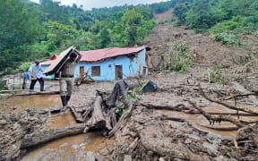 A security personnel carries the belongings of a villager from the site of a landslide after heavy rains at Jadon village in Solan district of India's Himachal Pradesh state on 14 August 2023. At least 16 people have been killed, nine of them in a temple collapse, and dozens more are feared missing after intense rains caused floods and landslides in India, officials said.