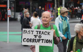 Protester at the March for Nature in Auckland protesting the Fast-track Approvals Bill holding a sign saying 'Fast track to corruption'.