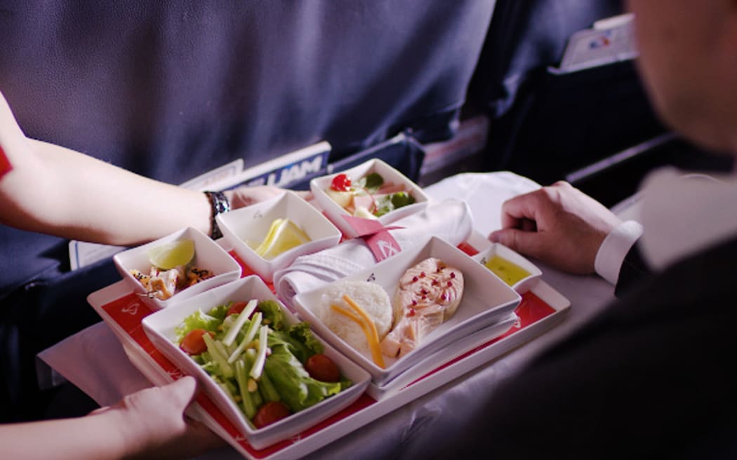 Stewardess holding tray with airline food on blue background.