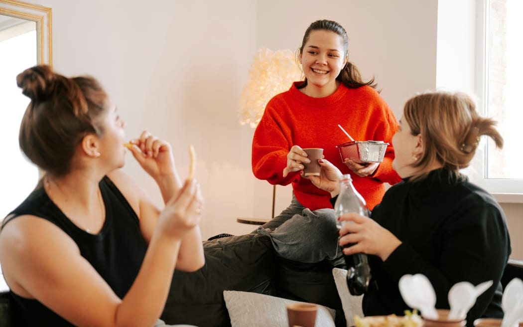 A group of friends gathered in a lounge, sharing food and drink.
