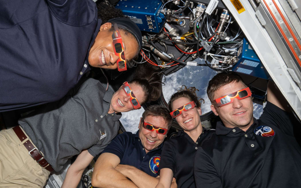 NASA astronauts aboard the International Space Station show off their eclipse glasses, which allow safe viewing of the Sun during a solar eclipse.