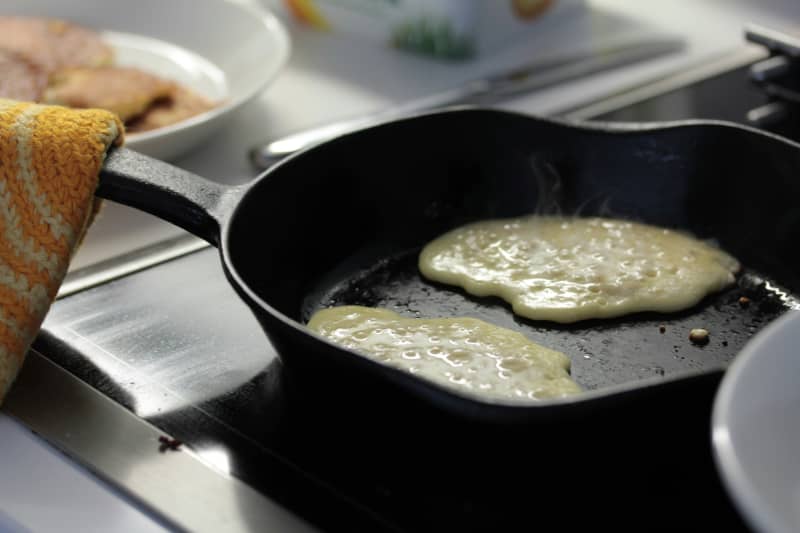 Pancakes being cooked on cast iron pan.