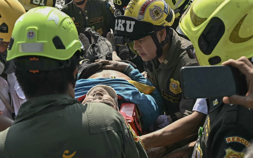 An injured man is rescued at a construction site where a building collapsed in Bangkok on March 28, 2025, after an earthquake. A powerful earthquake rocked central Myanmar on March 28, buckling roads in capital Naypyidaw, damaging buildings and forcing people to flee into the streets in neighbouring Thailand. (Photo by Lillian SUWANRUMPHA / AFP)